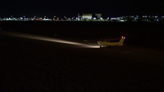 AX0023_001 - 5K aerial stock footage of small plane waiting at Kendall-Tamiami Executive General Airport at night, Florida