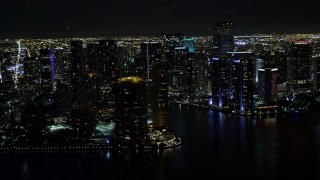 AX0023_057E - 5K aerial stock footage of flying by high-rises on the shore of Brickell Key at night and reveal river in Downtown Miami, Florida