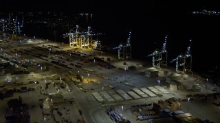 AX0023_060E - 5K aerial stock footage approach cargo cranes and ship at the Port of Miami at night, Florida