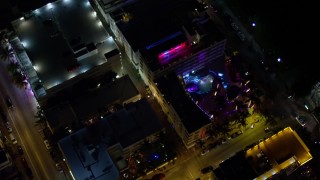 AX0023_116 - 5K aerial stock footage bird's eye view of a South Beach hotel with bright lights at nighttime, Florida