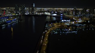 AX0023_135 - 5K aerial stock footage tilt from the MacArthur Causeway to reveal skyscrapers in Downtown Miami at night in Florida