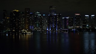 AX0023_153E - Aerial stock footage of 5K aerial \video tilt from the bay to reveal waterfront towers of the Downtown Miami at night, Florida