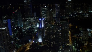 AX0023_158E - 5K aerial stock footage tilt from elevated rail and office building to reveal skyscrapers at night in Downtown Miami, Florida
