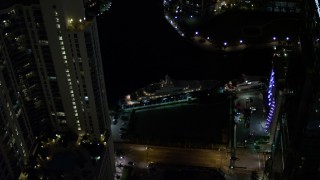 AX0023_170E - 5K aerial stock footage flyby yacht on the river and Downtown Miami skyscrapers at night, Florida
