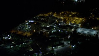 AX0023_183E - 5K aerial stock footage approach Mercy Hospital at night in Coconut Grove, Florida