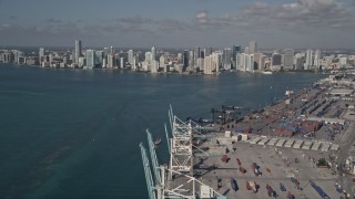 AX0024_115E - 5K aerial stock footage fly over cranes, cargo containers, Port of Miami, reveal Downtown Miami, Florida