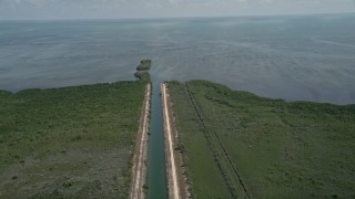 AX0025_012 - 5K aerial stock footage of orbiting canal to Atlantic Ocean in Mangrove Preserve, Homestead, Florida
