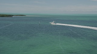 AX0025_095E - 5K aerial stock footage of following a fishing boat speeding past mangroves, Tavernier, Florida