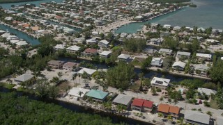 AX0025_104E - 5K aerial stock footage of approaching homes on canals along shore, Islamorada, Florida