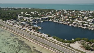 AX0025_129 - 5K aerial stock footage fly by Overseas Highway, neighborhoods, buildings on canals, Islamorada, Florida