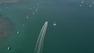 AX0026_083 - 5K aerial stock footage of following a speedboat racing past moored sailboats, Key West, Florida
