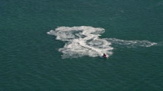 AX0026_088 - 5K aerial stock footage of a jet skier racing across the water in Key West, Florida
