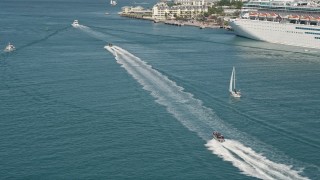 AX0026_099 - 5K aerial stock footage of a speedboat racing across water and tilt to more boats in Key West, Florida