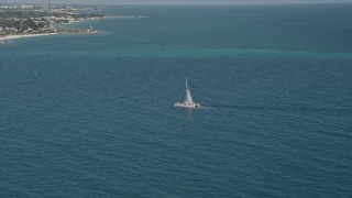 AX0026_107 - 5K aerial stock footage of flying by a catamaran near the shore of Key West, Florida