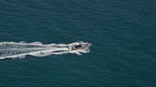 AX0026_108 - 5K aerial stock footage of a boat racing across the water near the shore of Key West, Florida