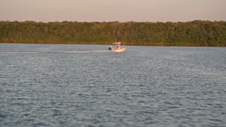 AX0028_031E - 5K aerial stock footage of tracking a fishing boat racing past mangroves at sunset, Key Largo, Florida