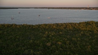 AX0028_033 - 5K aerial stock footage of flying over mangroves, approaching sailboats and fishing boat at sunset, Key Largo, Florida