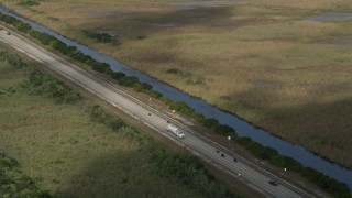 AX0030_060 - 5K aerial stock footage of tracking truck on highway, reveal motorcyclist, Florida Everglades, Florida