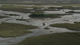 AX0030_063 - 5K aerial stock footage of tracking a fanboat racing through marshland, Florida Everglades, Florida