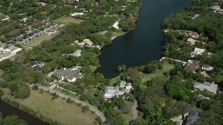 AX0031_002 - 5K aerial stock footage approach residential neighborhood, tilt down to shore of lake, Coral Gables, Florida