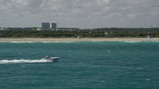 AX0031_072 - 5K aerial stock footage of a speedboat cruising near the shore, Bal Harbour, Florida