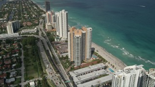AX0031_085 - 5K aerial stock footage of approaching condominium complex on shore, tilt down, Sunny Isles Beach, Florida