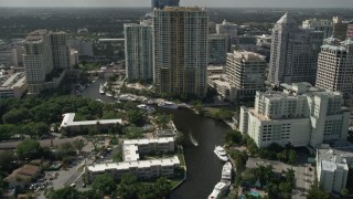 AX0031_114E - 5K aerial stock footage of following New River past mansions, revealing Downtown Fort Lauderdale skyscraper, Florida