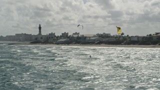 AX0031_170E - 5K aerial stock footage fly by kite surfers near coast, reveal Hillsboro Inlet Light, Hillsboro Beach, Florida
