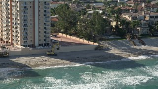 AX0032_033 - 5K aerial stock footage of flying by construction equipment on the beach, Highland Beach, Florida