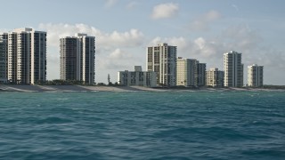 AX0032_118 - 5K aerial stock footage of passing by coastal condominium complexes, Riviera Beach, Florida