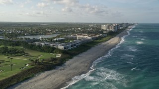 AX0032_127 - 5K aerial stock footage of flying along the coast by apartment buildings, Juno Beach, Florida
