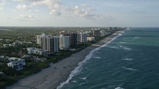 AX0032_128 - 5K aerial stock footage of following the beach, approaching condominium complexes, Juno Beach, Florida