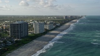 AX0032_129 - 5K aerial stock footage of following the beach by apartment buildings, Juno Beach, Florida