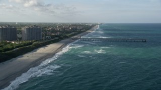 AX0032_131 - 5K aerial stock footage of following the beach, approaching the pier, Juno Beach, Florida
