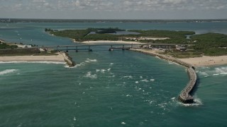 AX0033_065E - 5K aerial stock footage of flying by a bridge spanning an inlet with crystal blue waters, Vero Beach, Florida