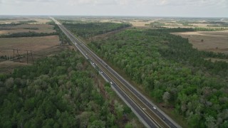 AX0034_064E - 5K aerial stock footage of following an Expressway through trees and a rural area, La Belle, Florida
