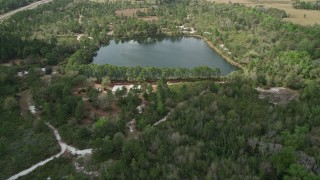 AX0034_066 - 5K aerial stock footage of approaching a small lake and campground among trees, La Belle, Florida