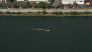 AX0035_010E - 5K aerial stock footage of tracking a toy speedboat racing around in a pond, Orlando, Florida
