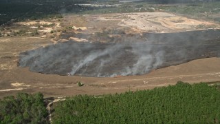 AX0035_095 - 5K aerial stock footage of approaching a burn area and flames at a farm field, Winter Garden, Florida