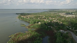 AX0035_112E - 5K aerial stock footage tilt from shore to reveal and approach homes by Lake Apopka, Florida