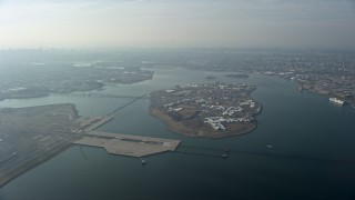 AX0065_0035 - 5K stock footage aerial video of Rikers Island on the East River as a commercial jet approaches LaGuardia Airport, Queens, New York City, winter