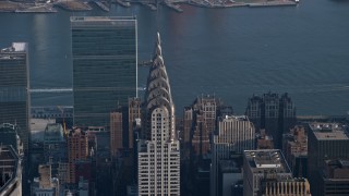 AX0065_0062 - 5K aerial stock footage of the top of the Chrysler Building, United Nations in the background, Midtown Manhattan, New York City, winter