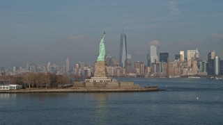 AX0065_0082 - 5K aerial stock footage flyby Statue of Liberty to focus on Freedom Tower and Lower Manhattan skyline in the distance, New York City, winter