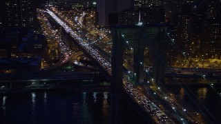 AX0065_0282 - 5K aerial stock footage track an arch in the Brooklyn Bridge with heavy traffic, Lower Manhattan, New York City, winter, night