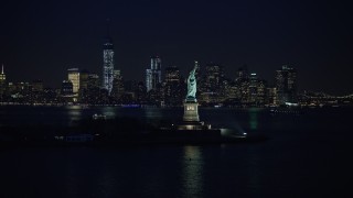 AX0065_0285E - 5K aerial stock footage flyby Statue of Liberty to approach the skyline of Lower Manhattan, New York City, winter, night