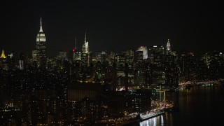 AX0065_0303 - 5K aerial stock footage of riverfront power plant, Empire State Building, and Midtown Manhattan skyline, New York City, winter, night
