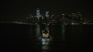 AX0065_0386E - 5K aerial stock footage track Staten Island Ferry sailing New York Harbor, reveal Lower Manhattan skyline, New York City, winter, night