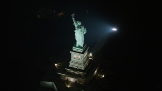 AX0065_0392E - 5K aerial stock footage of a slow approach to the Statue of Liberty in New York, winter, night, tilt to bird's eye view
