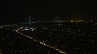 AX0065_0396E - 5K aerial stock footage of Verrazano-Narrows Bridge seen from Brooklyn neighborhoods in New York City, winter, night