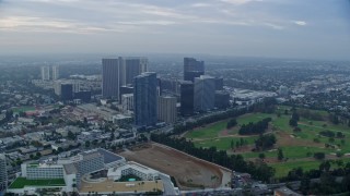 AX0156_131 - 7.6K aerial stock footage orbiting office buildings and skyscrapers toward golf course, sunrise, Century City, California